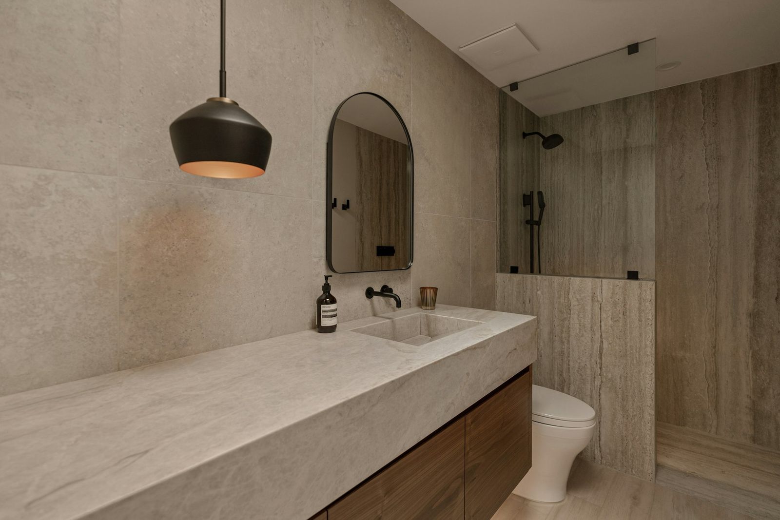 Bathroom with a long stone vanity, pendant light and walk-in shower