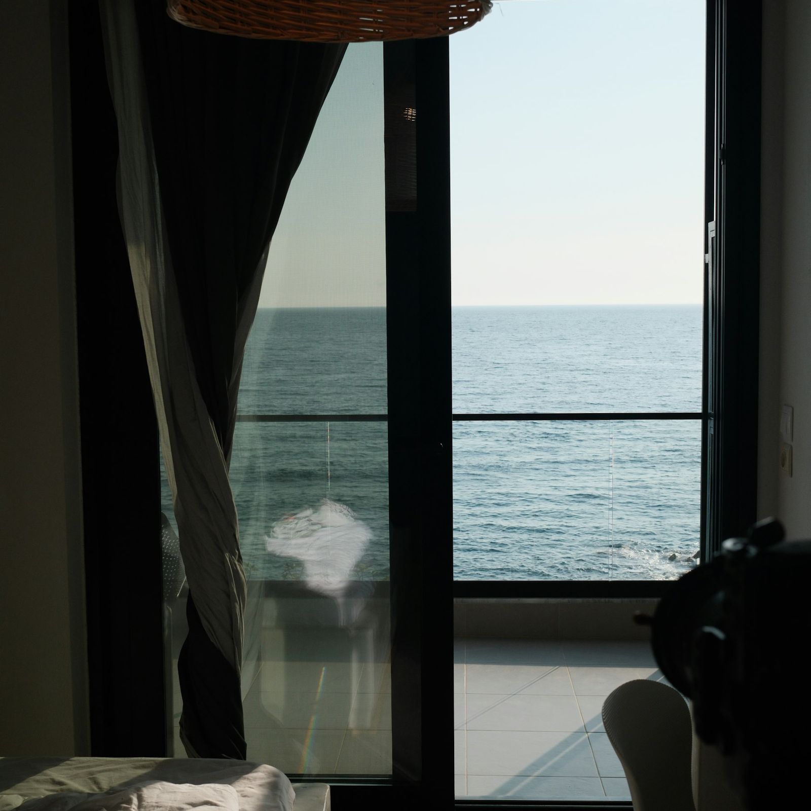 Light curtain at an open window with a calm sea beyond