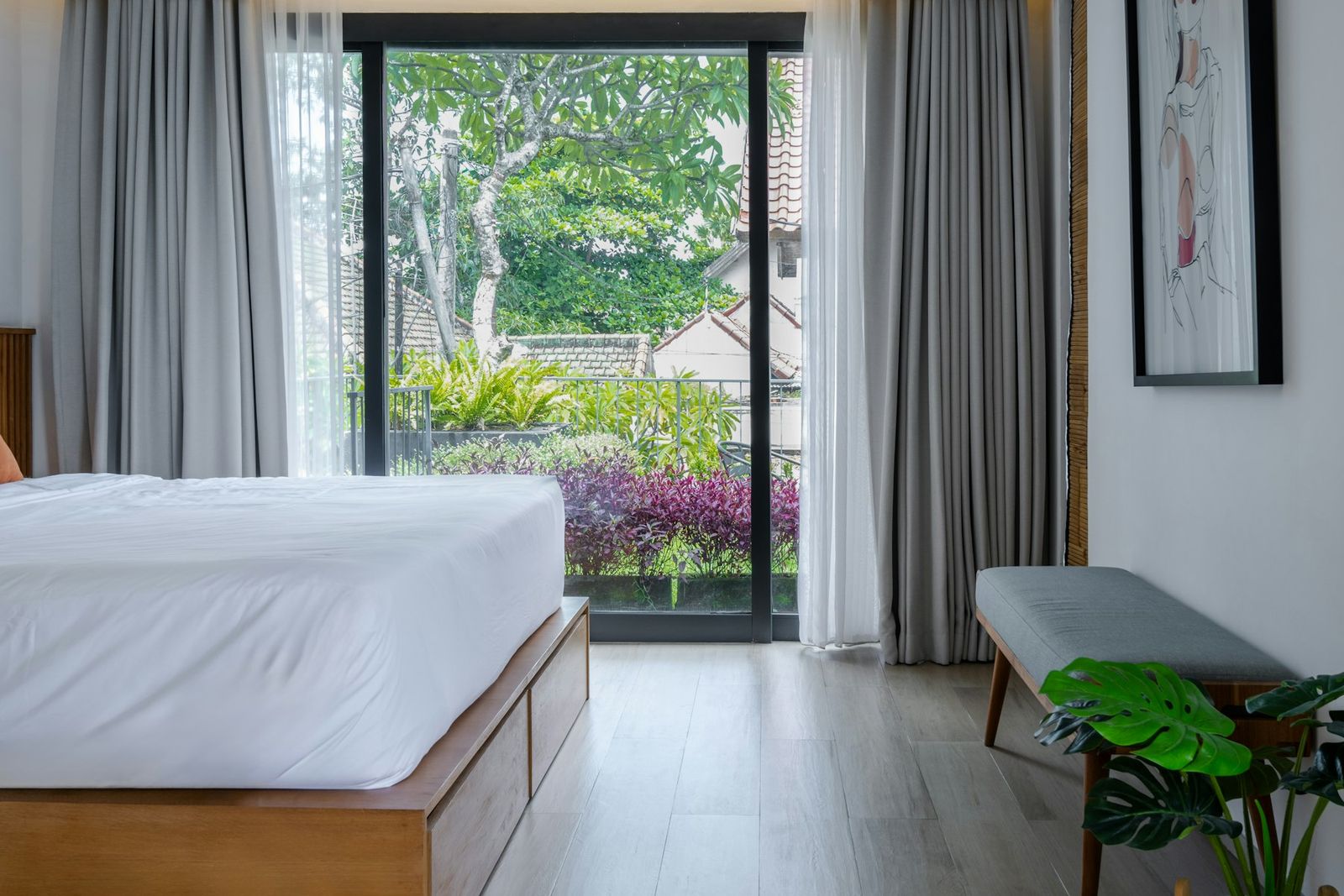 Bedroom with white linen and tall glass doors opening onto the garden