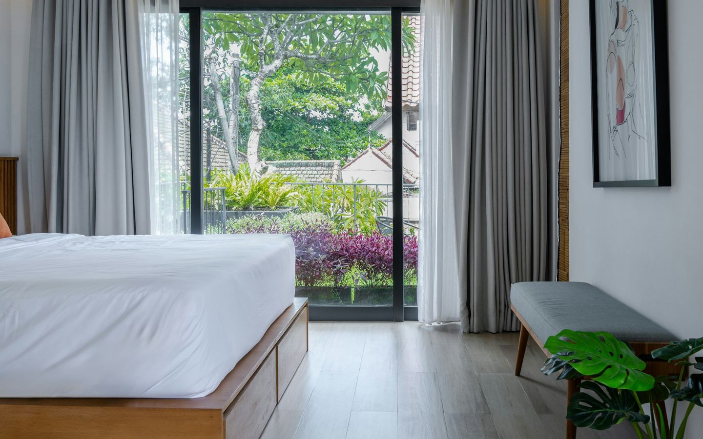 Bedroom with white linen and tall glass doors opening onto the garden